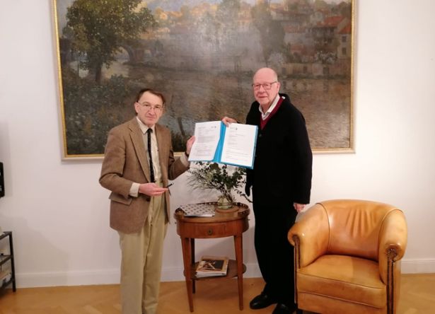 Peter Strasser und Bernd von Droste vor Gemälde den Vertrag der Übergabe des Vorlasses in Händen haltend