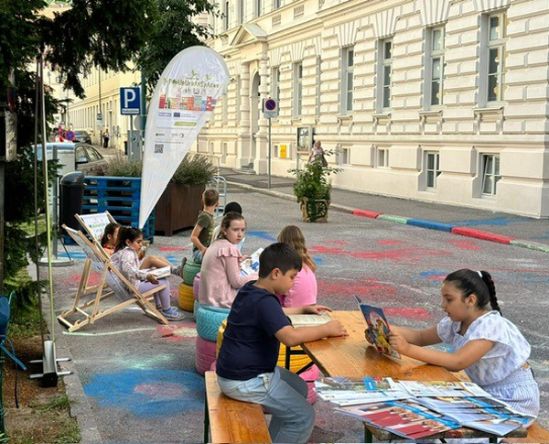 Kinder lesen auf der bemalten Straßenfläche des Hafnerplatzes
