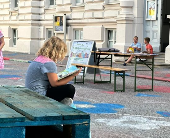 Kind liest auf bemalter Straßenfläche am Hafnerplatz