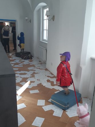 Skulpturen von Menschen n einem Gang mit weißen Zetteln am Boden