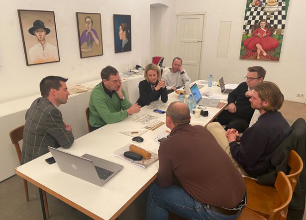 Teilnehmer_innen um großen Tisch in Besprechung