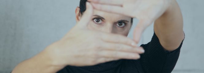 Eine Frau hält die Hände in einem Viereck vor ihr Gesicht.