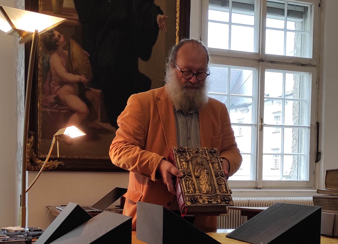 Mann hält den Codex Millenarius Maior in die Kamera