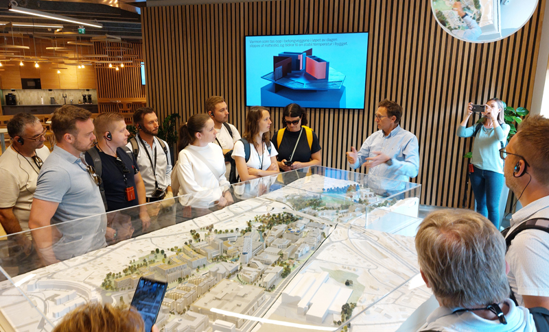 Teilnehmer_innen stehen im Kreis vor einem Bauprojektmodell