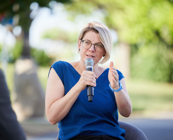 sitzende Dame mit Brille und blauem T-Short spricht in Mikro