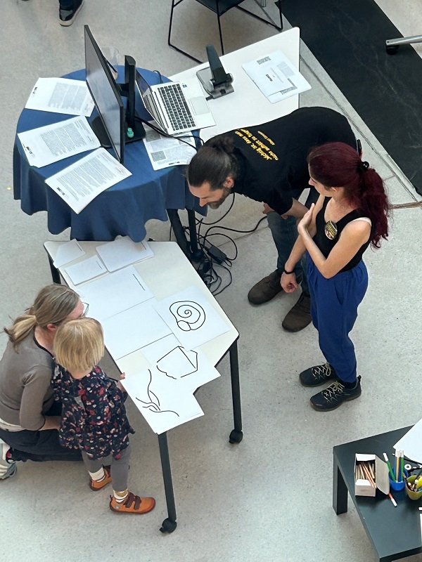 Foto von oben zeigt Personen, die sich bei Messestand informieren