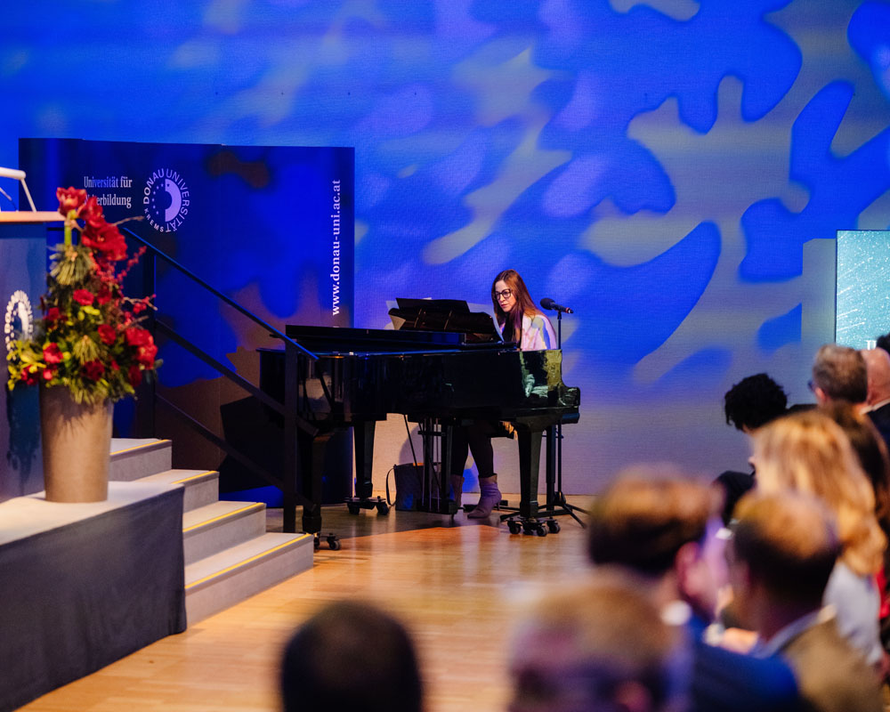 Musikerin am Klavier mit stimmungsvollem blauen Hintergrund