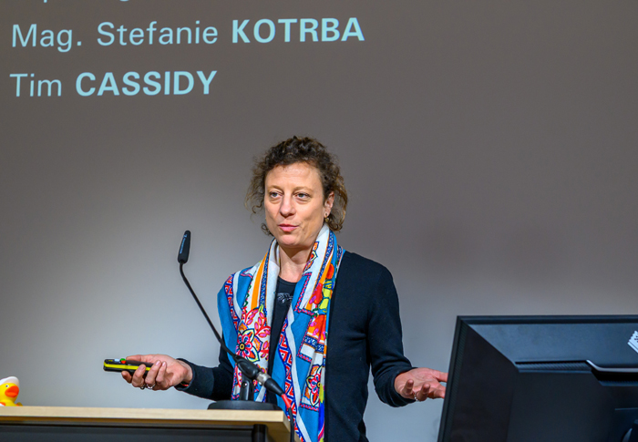 Frau mit blauem Short und buntem Schal vor Schwanenhalsmikrophon