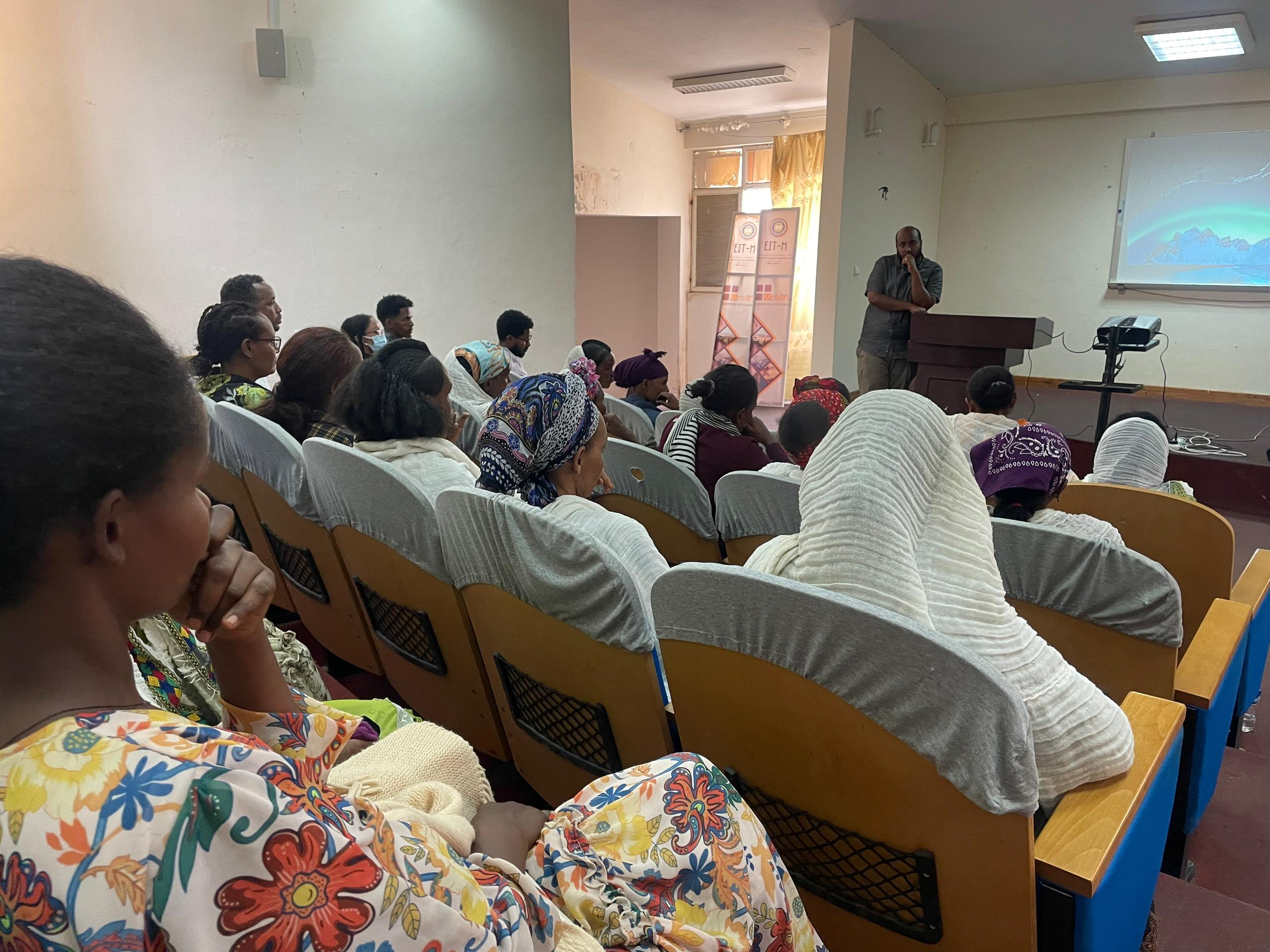 afrikanische Frauen in Hörsaal hören Redner in grauem Anzug zu