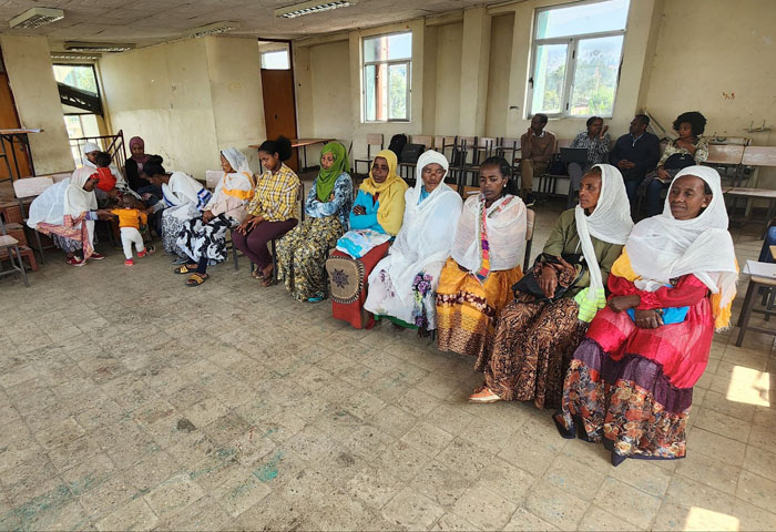 colorfully dressed African women sit in a hall
