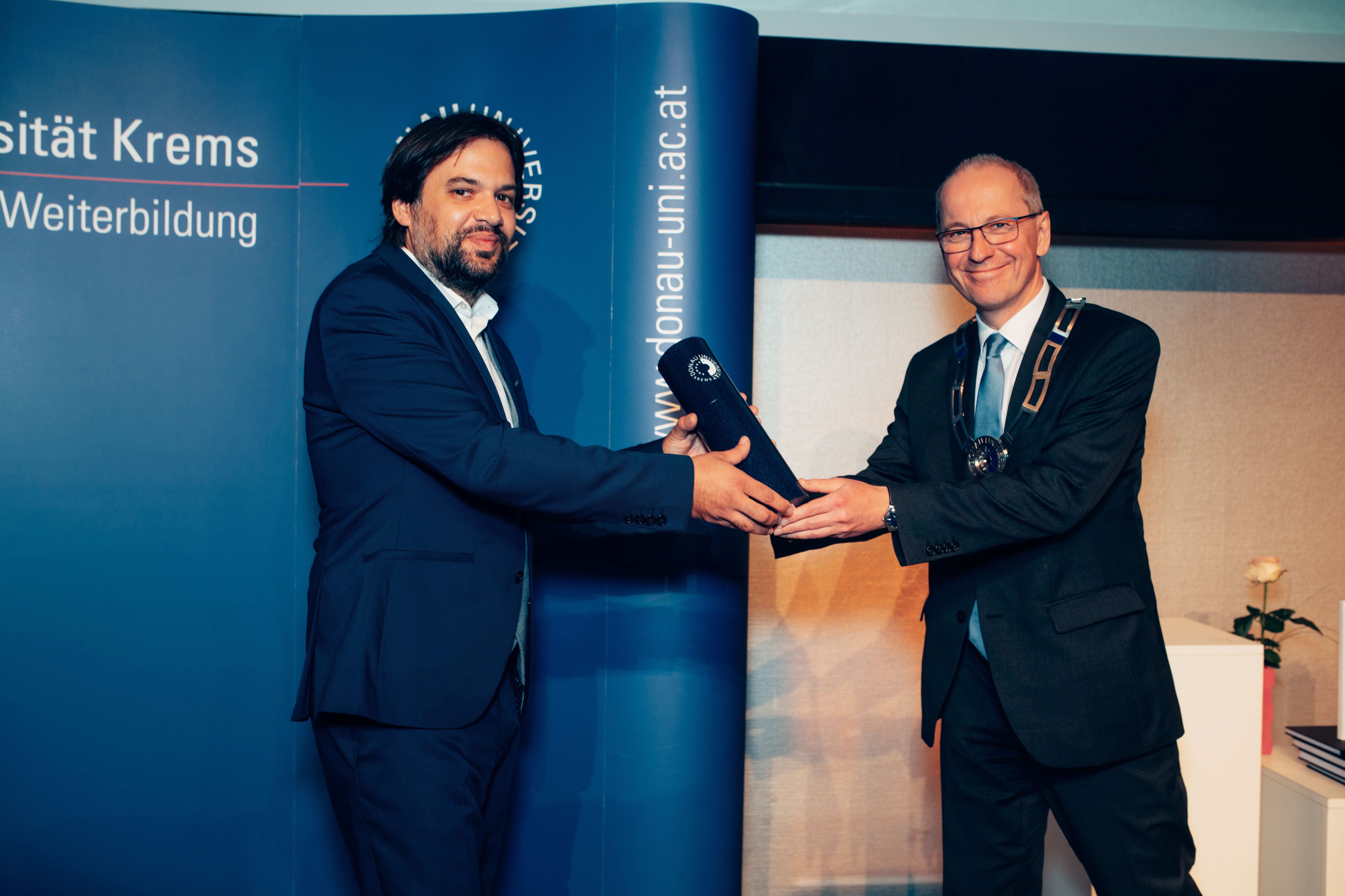 Mag. Friedrich Faulhammer, Rektor der Universität für Weiterbildung Krems, übergibt Mag. Dino Pitoski, MSc, PhD die Promotionsurkunde.