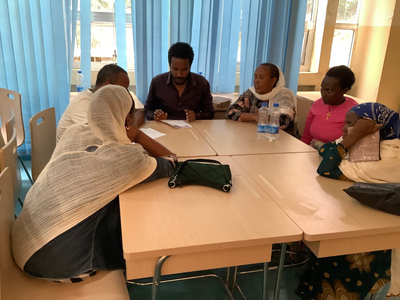 Menschen sitzen um zusammengeschobene Schulbänke und diskutieren