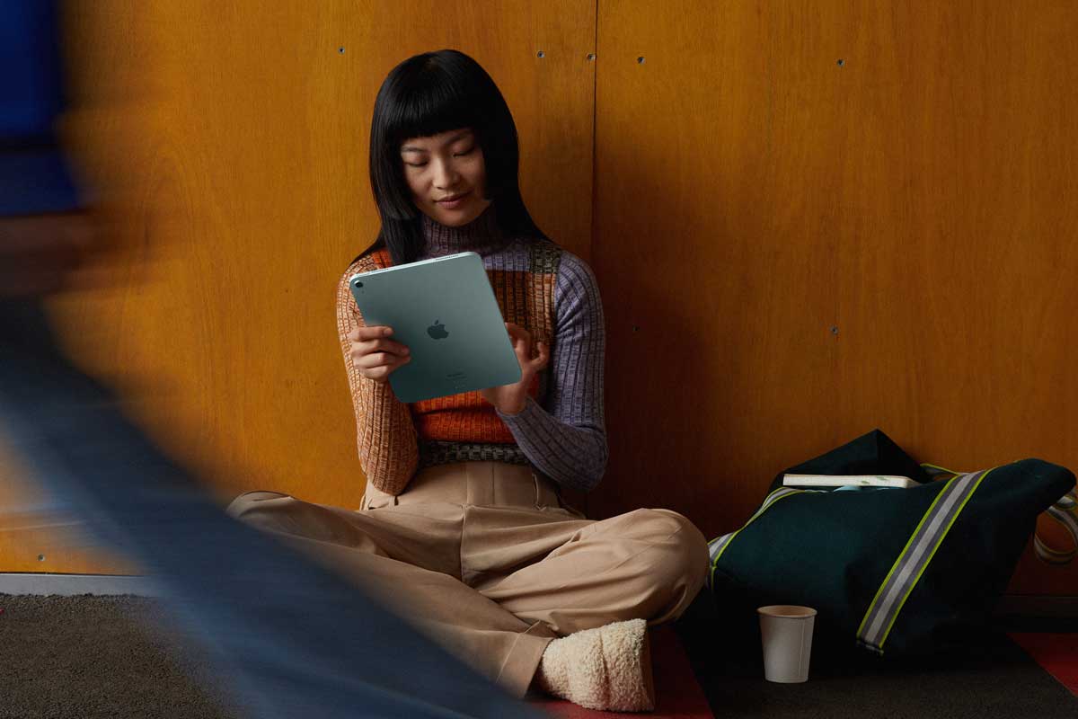 © Apple Asiatische junge Frau sitzt am Boden und arbeitet auf ihrem iPad.